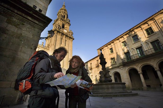 Dos peregrinos con mochila consultando un plano de la ciudad en la plaza de Plat
