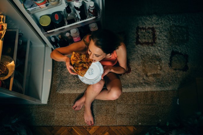 Mujer comendo al lado de la nevera, ansiedad, atracón, hambre