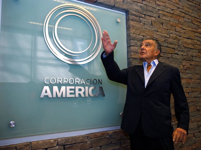 Argentine business magnate Eduardo Eurnekian poses next to a logo of his company