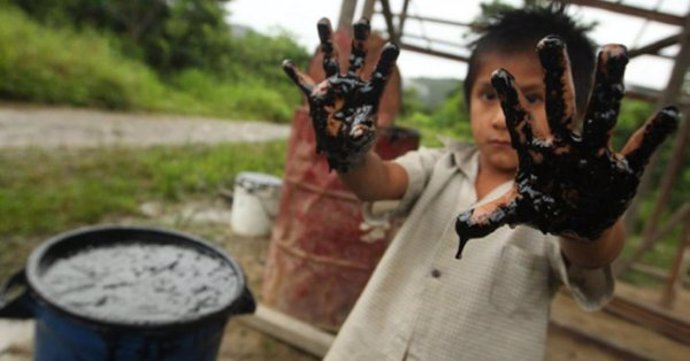 Niño de un pueblo amazónico con  las manos manchadas de petróleo