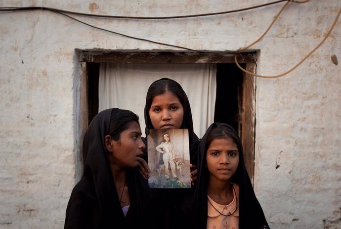 Las hijas de la cristiana paquistaní Asia Bibi posan con una foto de su madre