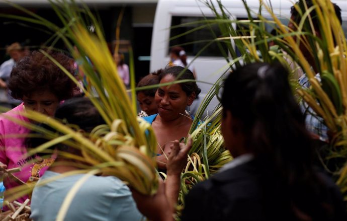 A woman buys crosses made out of palm fronds for the oncoming Palm Sunday in Teg