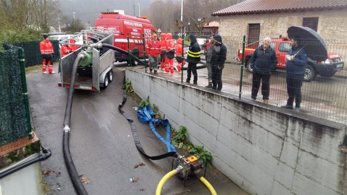 Efectivos de emergencias achican agua en un garaje