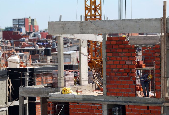 A worker is seen at a the construction site of an apartment building next to a s
