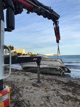 Una grúa retira un barco varado en la playa de S'Estanyol