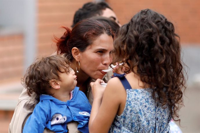 A Venezuelan migrant child feeds her mother during the inauguration of a tempora