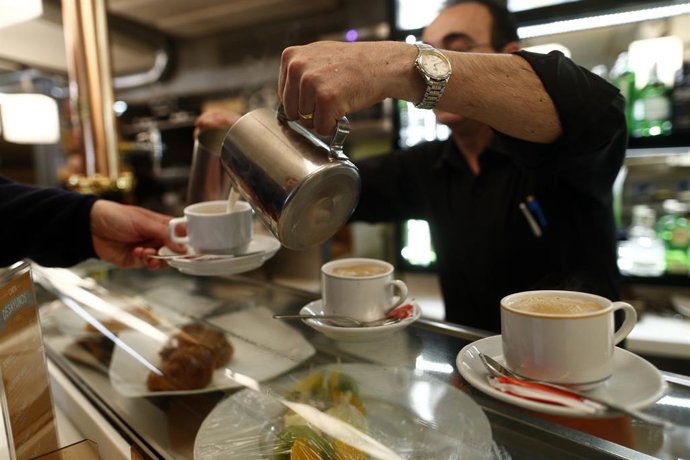 Un camarero sirve cafés en un bar