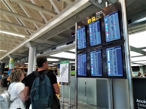 Dos viajeros consultan la informaciÃ³n de vuelos en las pantallas del aeropuerto