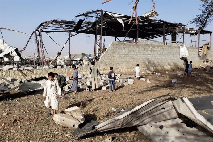 Niños yemeníes junto a un edificio destruido en un bombardeo
