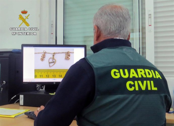 En la imagen un agente de la Guardia Civil observa las pruebas y joyas robadas o