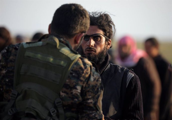 Combatiente de las FDS registra a un hombre cerca de Baghuz, en el este de Siria