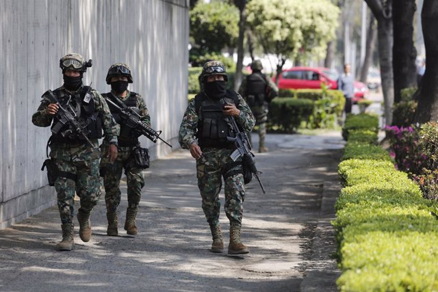 Military personnel walk on a sidewalk after security was stepped up outside the 