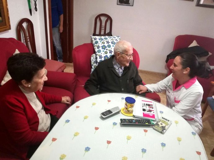 Una trabajadora del servicio de ayuda a domicilio conversa con dos usuarios.