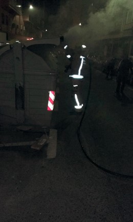 Un bombero trata de extinguir un contenedor en Alicante.