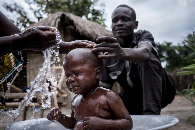 Un padre lava a su hijo de tres años a las afueras de Bangui, en RDC