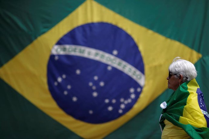 A woman is seen with a Brazilian flag in front of the National Congress during a