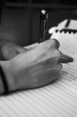 Persona escribiendo en un papel con un bolígrafo