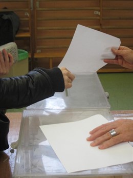 Una mano deposita una papeleta en la urna en un colegio electoral