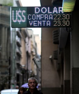 A man looks at an electronic board showing currency exchange rates in Buenos Air