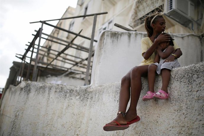 Una mujer con su hija en los cascotes de un efificio destruido en Israel