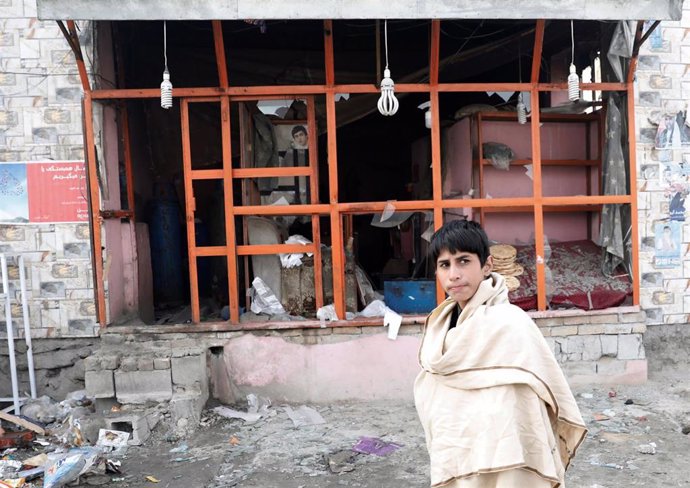 Un niño afgano camina por delante del lugar de la explosión en Kabul, Afganistán