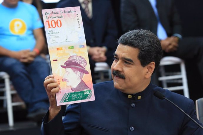 Venezuela's President Nicolas Maduro holds a sample of the new hundred bolivars 