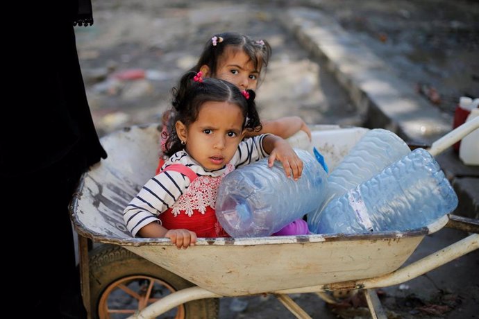 Dos niñas esperan el reparto de ayuda humanitaria en Saná