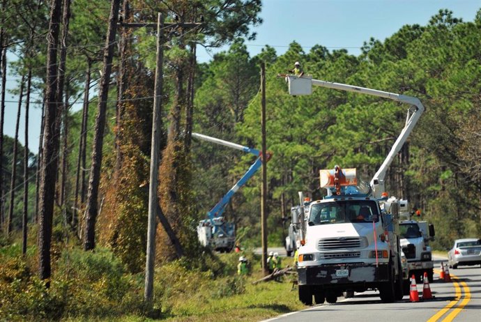 Reparan postes de luz en Florida tras el paso del huracán Michael.