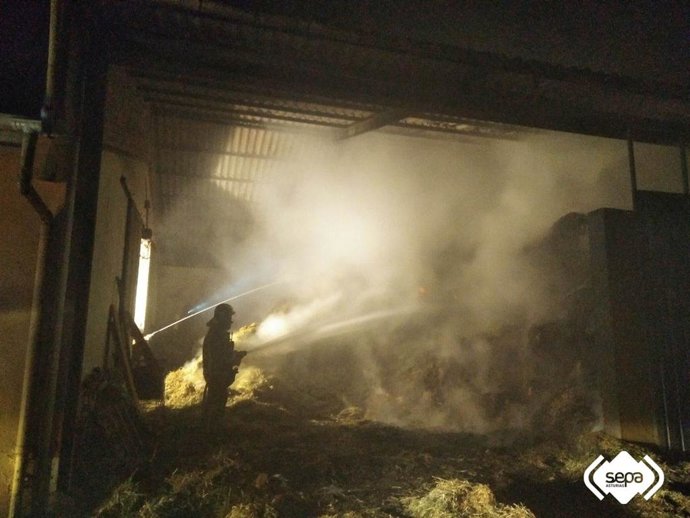 Bombero apaga un incendio en una nave agrícola en La Follaca, Nava
