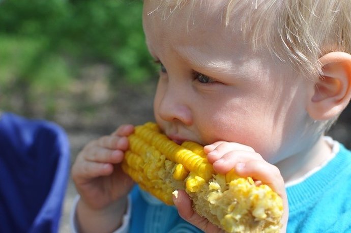 Niño comiendo maíz