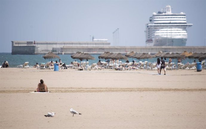 Una mujer descansa en la arena de la playa de la Malvarrosa de Valencia en un soleado día, víspera del inicio del estío.