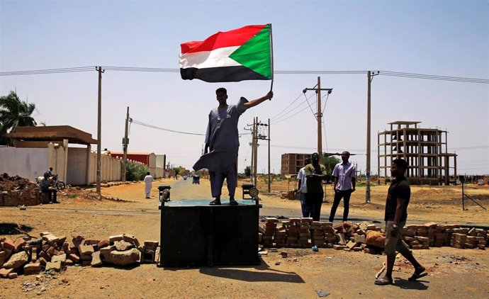 Un manifestante con la bandera de Sudán en una barricada en Jartum