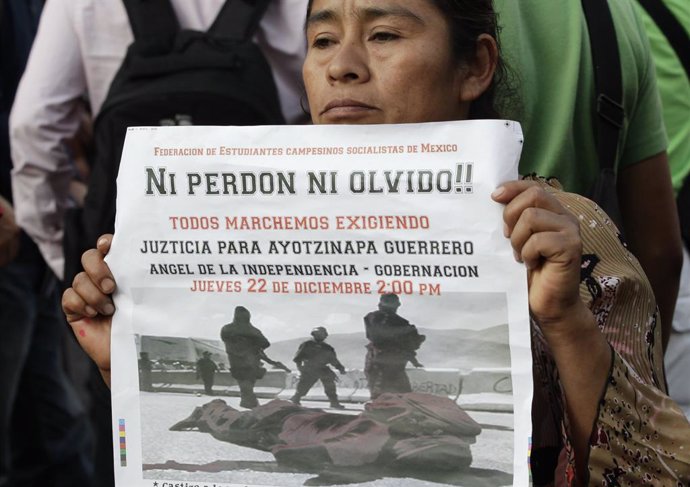 A woman from a civil organization holds a poster as she takes part in a protest demanding justice for the death of two students in Ayotzinapa, during a march on streets in Mexico City