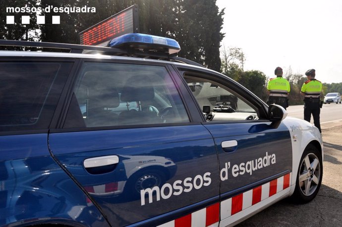 Agentes de los Mossos d'Esquadra junto con su coche.