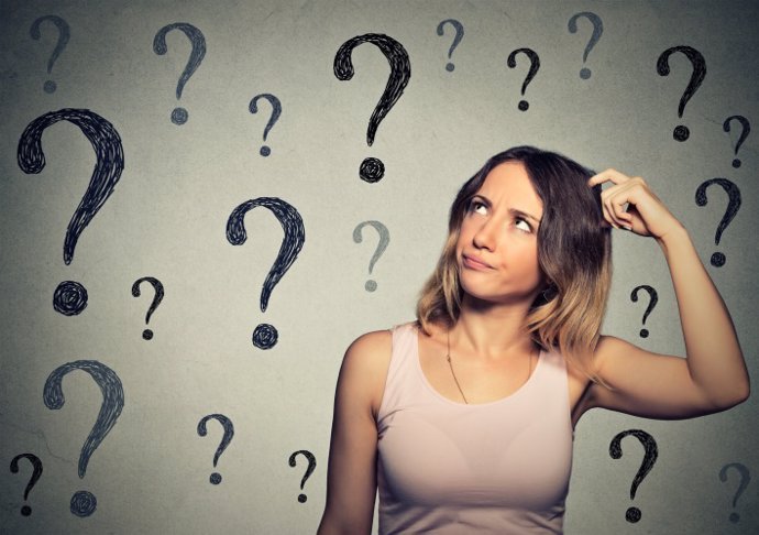 Thinking woman looking up at many question marks