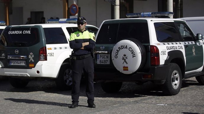 Agente de la Guardia Civil, a su espalda dos coches de la Guardia.