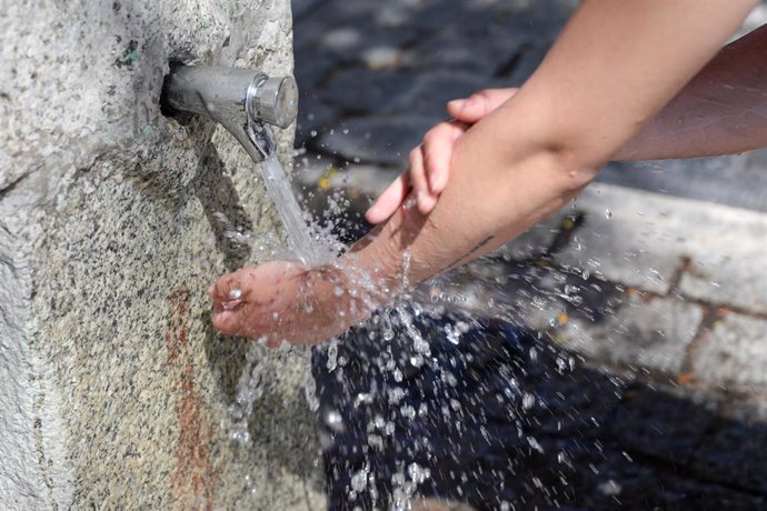 Un joven se moja las manos y brazos en una fuente de Madrid Río para refresercarse de las altas temperaturas  un día antes de que, según la Agencia Estatal de Meteorología (AEMET), llegue a la península Ibérica y a las Islas Baleares la primera ola de c