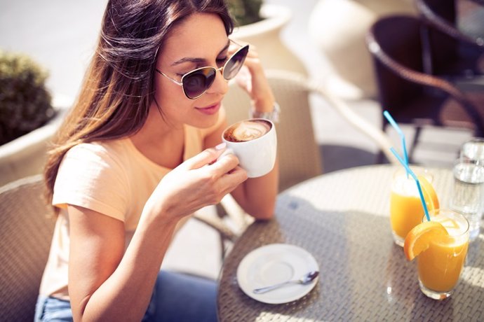 Mujer desayunando café y zumo de naranja en una cafetería