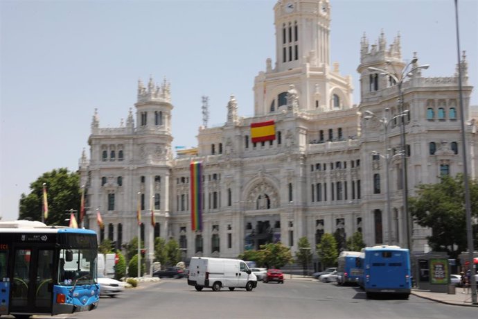 Fachada del Palacio de Cibeles, sede del Ayuntamiento de Madrid, donde ondean dos banderas de España (una de gran tamaño impuesta por Vox)  y la bandera LGTBI en la parte izquierda del edificio.