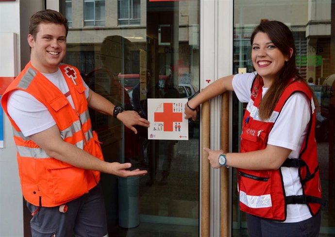 Delegados de Cruz Roja enseñan el pictograma para personas con autismo colocado en las sedes