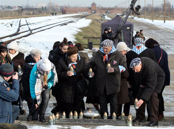 27 January 2019, Poland, Oswiecim: Holocaust survivors and their relatives place candles on a plaque at the memorial of the former German Nazi concentration camp Auschwitz-Birkenau on the occasion of the International Holocaust Memorial Day and the 74th