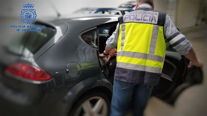 Un agente de la Policía Nacional ayuda a salir del vehículo a un camarero detenido por copiar datos de tarjetas de crédito y pagar con ellas en internet.