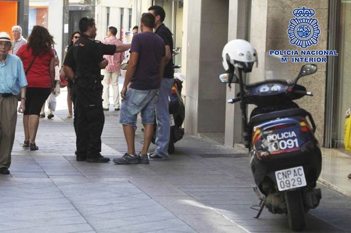 Un policía atiende a unos ciudadanos en una calle este verano