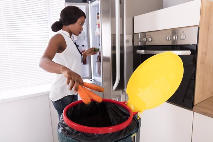 Mujer tirando zanahorias a la basura.