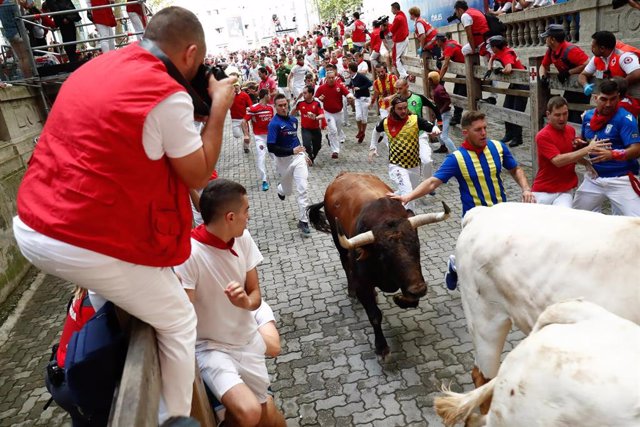 Decenas de personas corren en el segundo encierro de las fiestas de San Fermín con toros de la ganadería José Cebada Gago, a su llegada a la plaza.