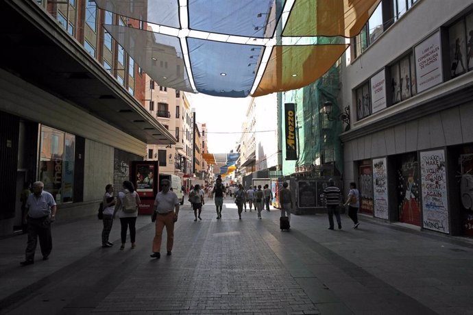 Turistas y vecinos de la zona Centro de Madrid pasean por la calle Preciados bajo la sombra gracias a los toldos instalados.