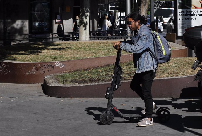 Un hombre montado en un patinete ecléctico en una calle de la capital española.