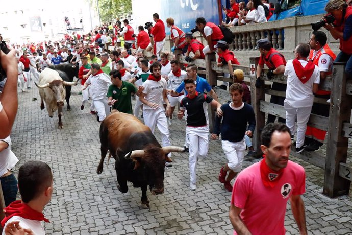 Decenas de personas corren en el segundo encierro de las fiestas de San Fermín con toros de la ganadería José Cebada Gago, a su llegada a la plaza.