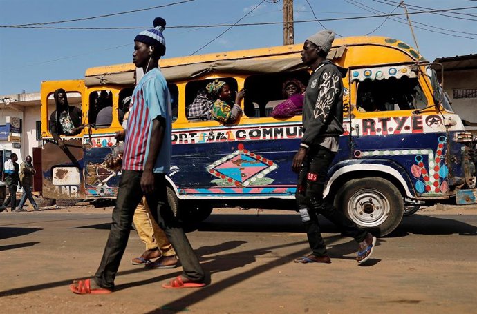 Personas caminan junto a un autobús en Senegal