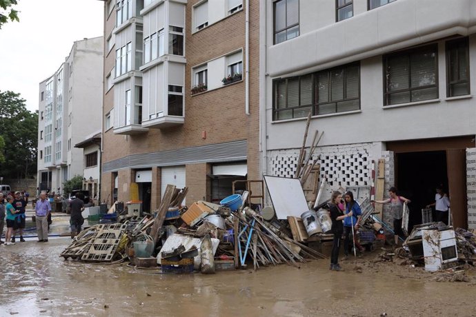 Varios vecinos limpian garajes tras las graves inundaciones en Tafalla.